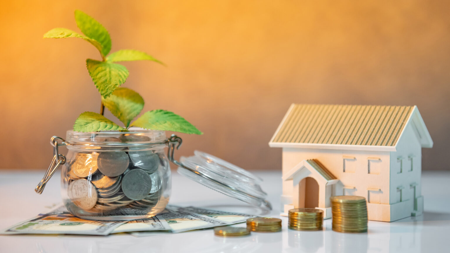 Maison miniature et économies représentant l'investissement dans une formation en immobilier.